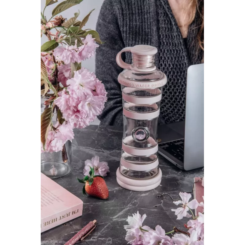 Bouteille i9 Compassion rose sur un bureau, près d'un ordinateur portable