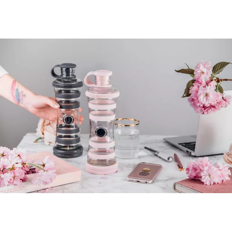 Bouteille i9 Compassion rose à côté d'une bouteille i9 foncée, sur un bureau