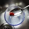 Colorant test Berkey® : de la poudre rouge sur une cuillère, au-dessus d'un bol d'eau